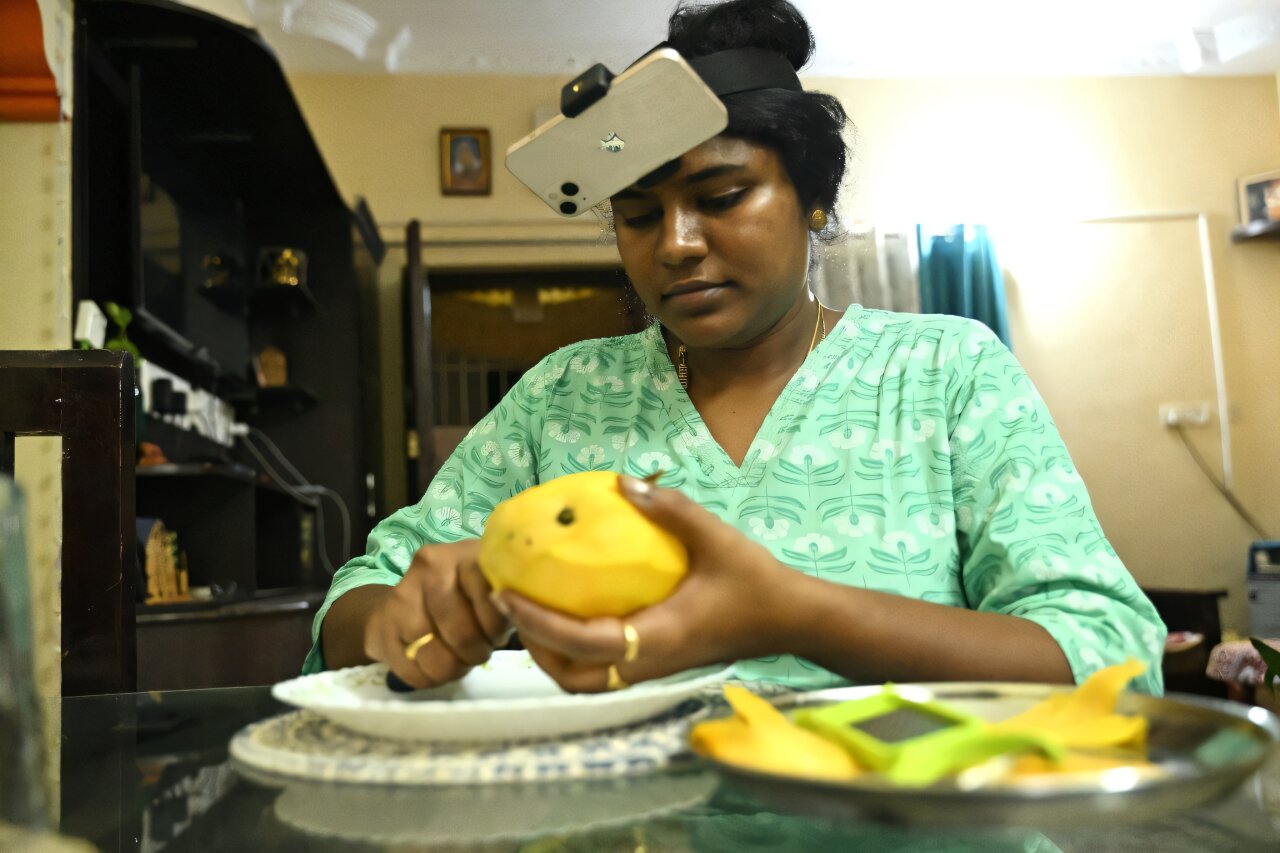 AI robotics training data graphic showing an Indian worker wearing a head camera while recording household tasks